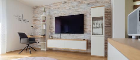 Wohnzimmer mit SmartTV und Arbeitsbereich der Premium Suite der Parkvilla Steins