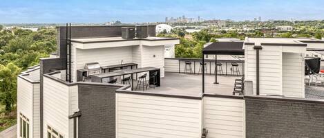 Spacious private rooftop deck featuring a BBQ grill with outdoor dining, and city views.