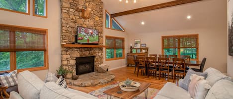 Living and dining area with stone fireplace, soaring vaulted ceilings and HDTV