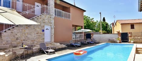 The exterior of the apartment with balcony, swimming pool in the garden.