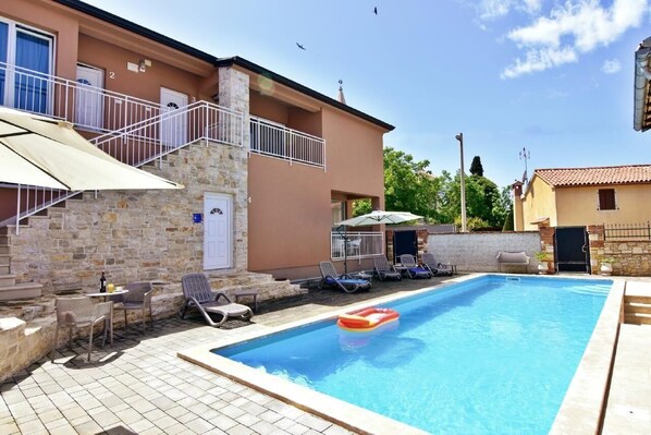 Das Äußere der Wohnung mit Balkon, Swimmingpool im Garten.