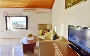The living area with two armchairs, a coffee table, satellite TV, air conditioner