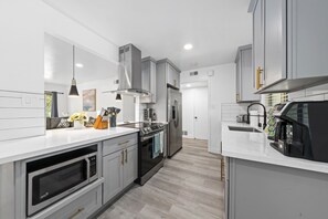 Fully Stocked Kitchen with Stainless Steel Electric Range and Island Hood