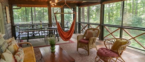 25 feet by 15 feet screened in porch with seating, hammocks, and dining table. 