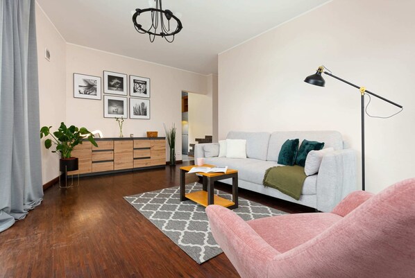 A cozy living room with wooden furniture, a light-colored sofa, and decorative plants, creating a homey ambiance.