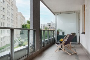 A spacious balcony with a small seating area, overlooking a modern urban view.