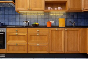 A kitchen featuring wooden cabinets, a tiled backsplash, and modern appliances, blending traditional and contemporary styles.