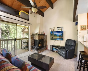 Living room with Smart TV, wood burning fireplace, and balcony access