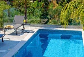 View of the large swimming pool with sunbeds for rest and relaxation in the famous luxury villa for rent  Raquel surrounded by greenery on the island of Šolta