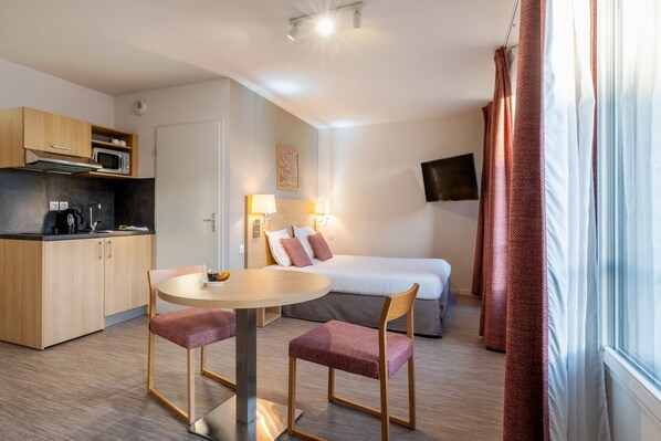 A cozy studio apartment featuring modern furnishings, a compact kitchenette, and warm lighting.