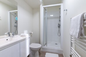 A clean and modern bathroom equipped with a shower, vanity sink, and fresh towels.