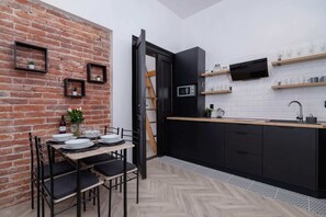 Fully equipped kitchenette with a kettle, fridge with freezer, microwave, coffee machine, washing machine and a dining area.