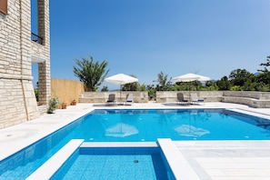 The swimming pool area with sunbeds and umbrellas