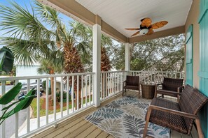 Relax on the balcony with comfy seating, a fan, and views of lush palm trees.
