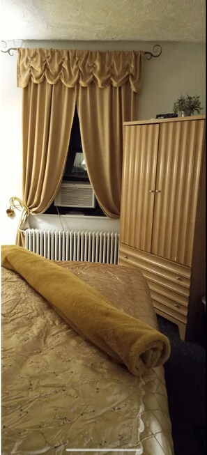 Bedroom with king size bed ,tv in armoir ,window air conditioner,dresser,closet