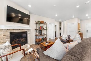 Cozy living area with ample seating, gas fireplace, flatscreen tv, and children&#39;s games/books provided.