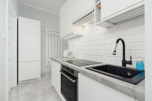 Modern, functional kitchen with black sink and appliances such as oven and hob.