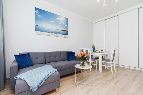 A comfortable lounge area with a cozy sofa, a TV, and large windows for ample sunlight.dc