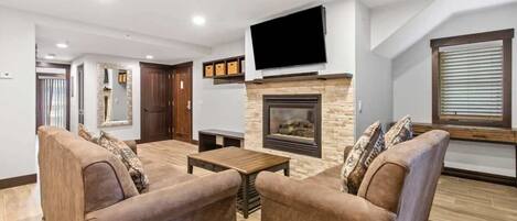 View of the family room with a cozy indoor gas fireplace, flat-screen TV, comfortable seating, and front door