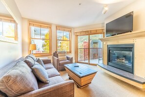 Living area with gas fireplace, mounted flat screen TV and queen sleeper sofa.