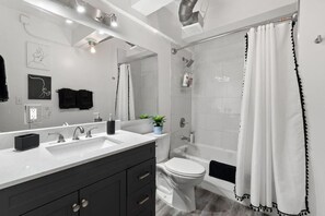 Spacious bathroom featuring a double vanity, bright lighting, and a clean, refreshing shower area.