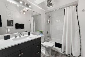 Spacious bathroom featuring a double vanity, bright lighting, and a clean, refreshing shower area.