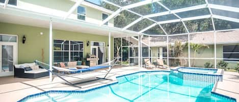 Enveloped in Tropical Bliss: A screened-in Pool Oasis with ample seating and lounge chairs