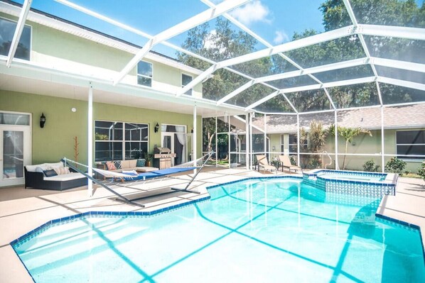 Enveloped in Tropical Bliss: A screened-in Pool Oasis with ample seating and lounge chairs