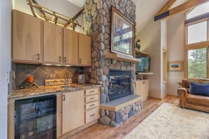 Living room with stone fireplace and wet bar.