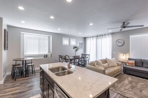 Kitchen Side View - The Kitchen and Dining Table can accommodate 10 adults and is stocked with pots, pans, baking sheets, mixing bowls, plates, bowls, cups, silverware, and a collection of cooking utensils.