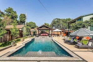  Extended pool tanning ledge with multiple seating areas and umbrellas.