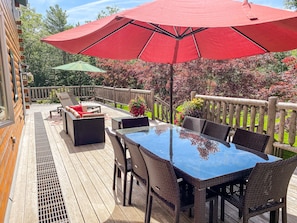 Enormous deck with 8 person table, sofa, and two chaise lounges.