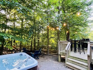 Back yard with deck overlooking wooded forest, with hot tub, gas fire pit