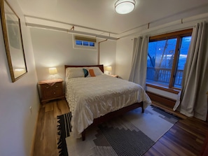The bedroom has a queen size bed, large window and black-out curtains.