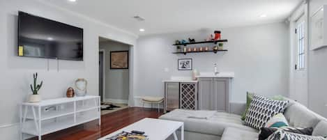 Living room with sectional sofa, wet bar, big screen smart tv, and rear courtyard access.