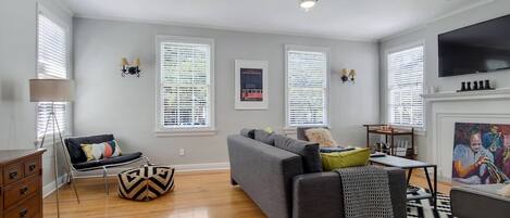 Living room features a sectional sofa & large screen smart tv.