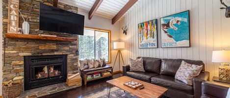 Living room with large TV and wood burning fireplace