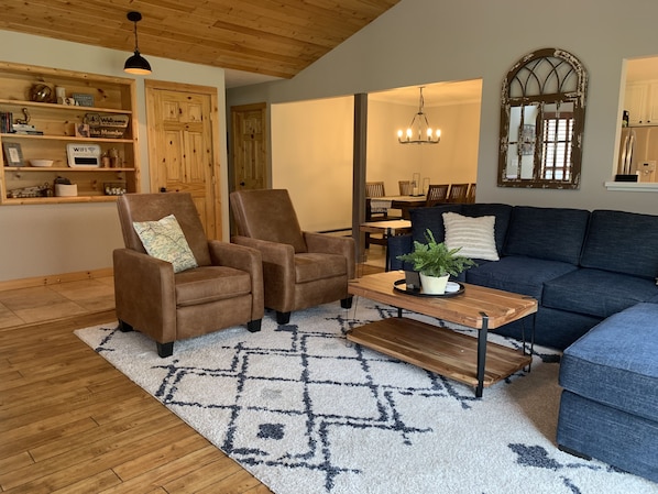 Spacious living room with vaulted ceilings,  cozy furniture, fireplace, and view