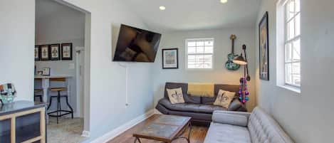 Living room with high ceilings, fold out bed, kitchen entrance to the left