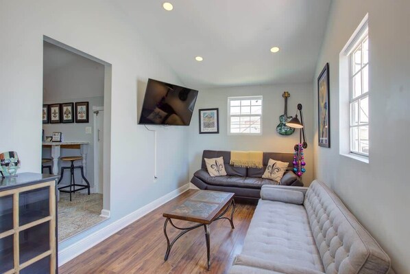 Living room with high ceilings, fold out bed, kitchen entrance to the left