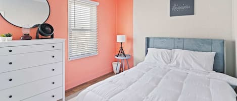 Bedroom #2 w/coral accent wall, comfortable queen bed, and twin daybed