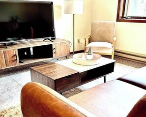 Living room with leather couch, coffee table, entertainment center with Roku TV