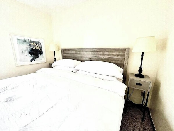 Bedroom with comfy queen matress, nightstand and bedside lamp