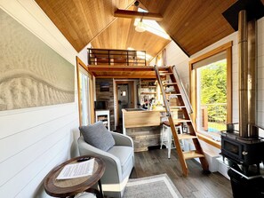Living area with custom ladder to the bedroom loft and wood burning fireplace 