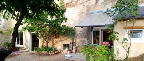 Entrée troglodyte  à droite avec terrasse en bois et auvent 