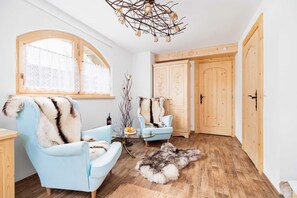  A spacious bedroom with wooden accents and a comfortable armchair. Large windows provide ample natural light and showcase scenic views.