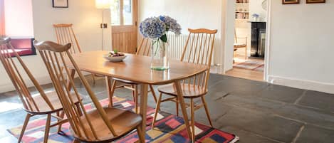 Characterful dining room with exposed beams and original slate floor, completed with a wood burner stove