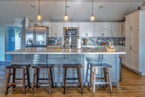 Chef's kitchen with cooking supplies, large island, and ample cabinet space.