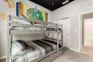 Second bedroom, with custom wall art, has a full size over full size bunk bed with a trundle beneath.