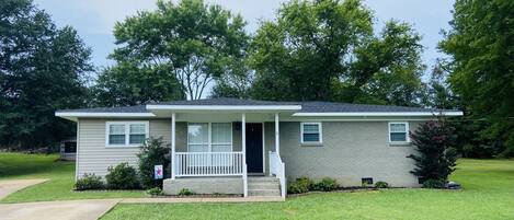 Front of the house with porch and concrete driveway. 